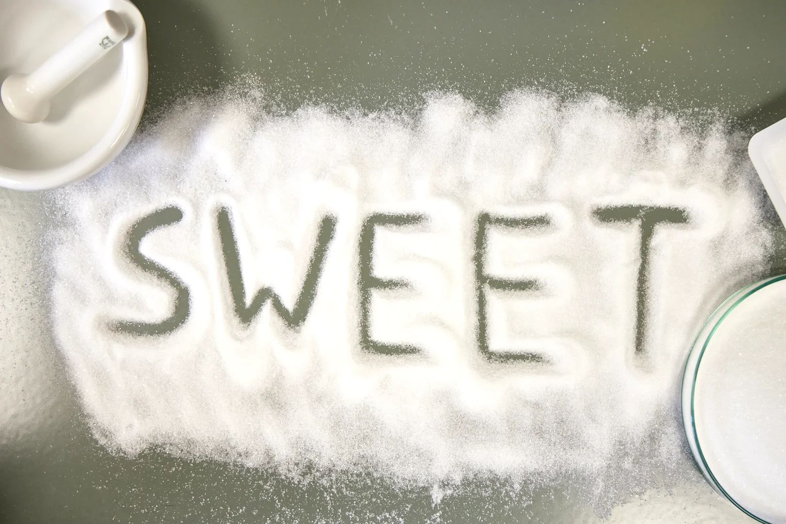 Eine Wissenschaftlerin und ein Wissenschaftler arbeiten hinter einer Glasfassade und mischen Chemikalien mit Großgeräten.